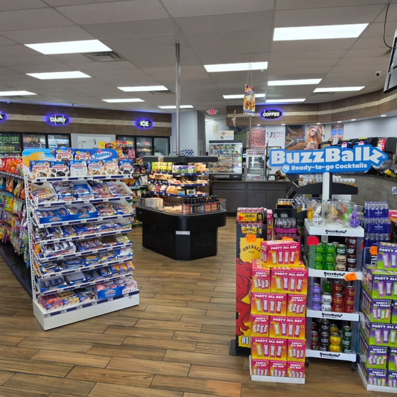 Store interior with snack racks, beverages in coolers along the left, and a BuzzBallz ready-to-go cocktails display in the foreground.