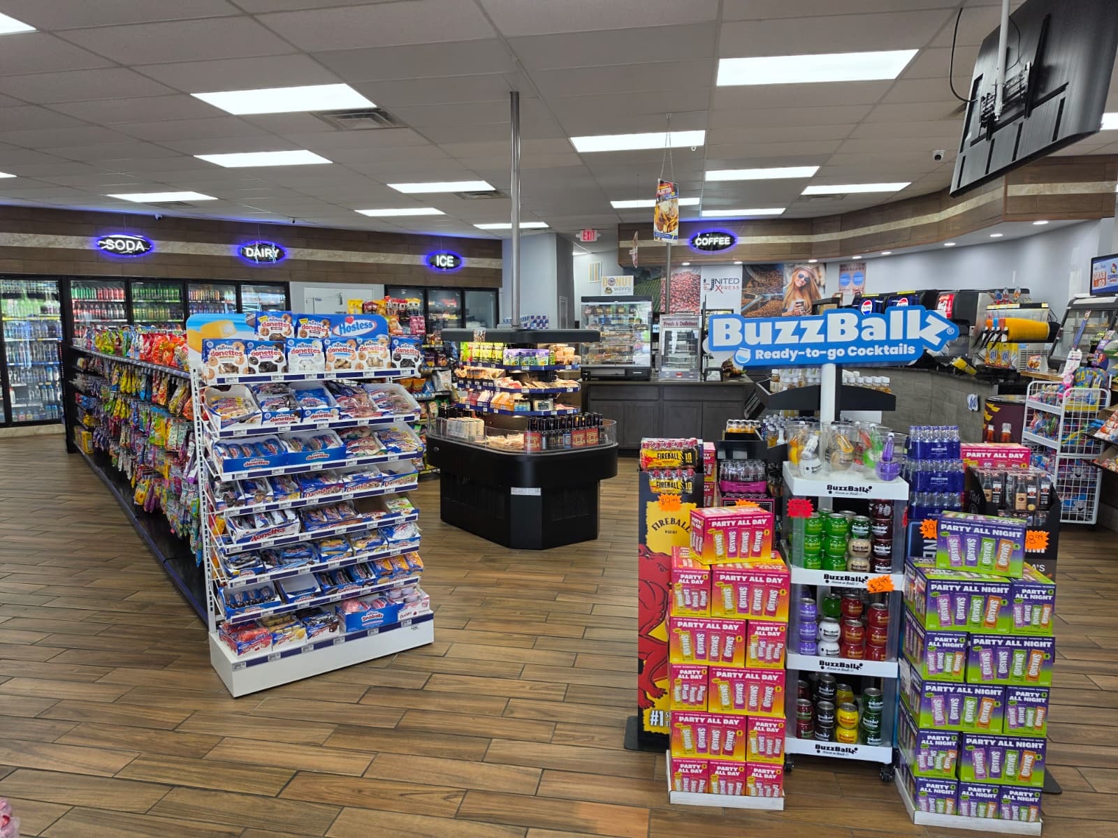 Store interior with snack racks, beverages in coolers along the left, and a BuzzBallz ready-to-go cocktails display in the foreground.