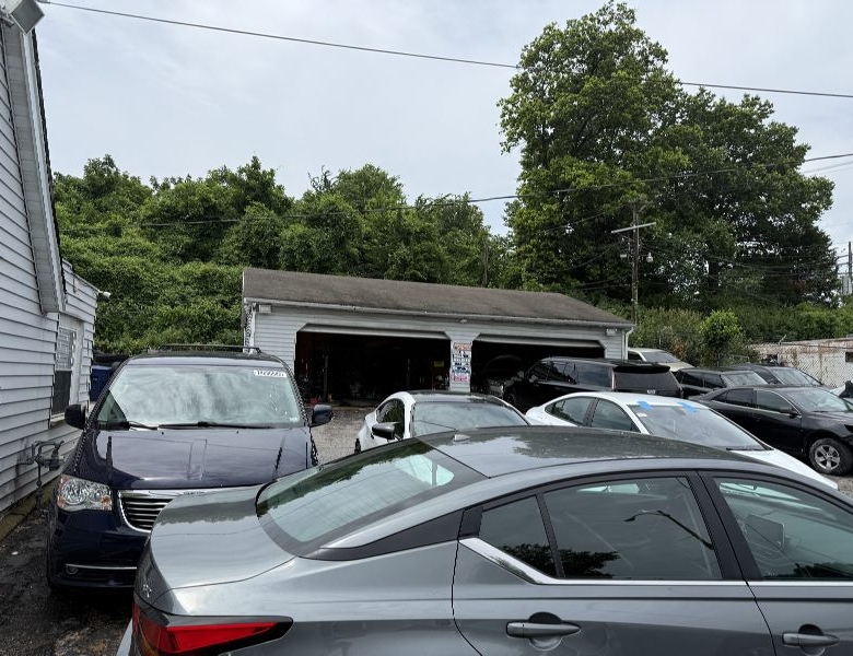 Small auto repair shop with a two-bay garage and several parked cars in front.
